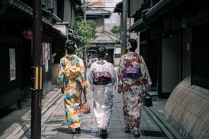 three geisha walking between buildings